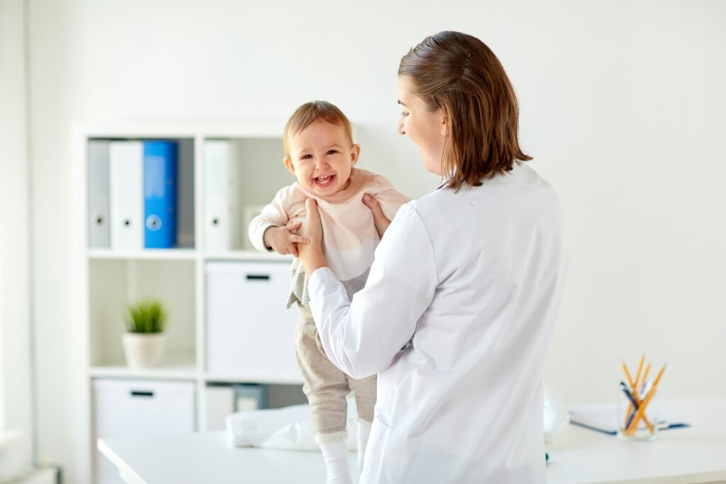 doctor or pediatrician holding baby at clinic