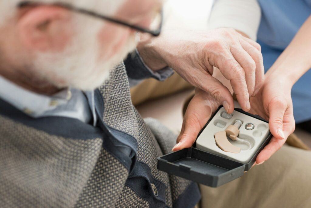 High angle view of elderly man looking at box with hearing aid